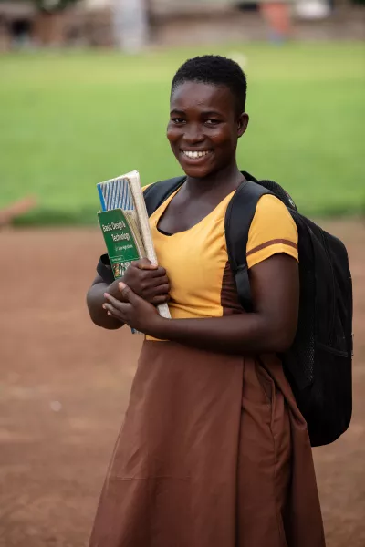 Jennifer, 18, holds her books outside of her school