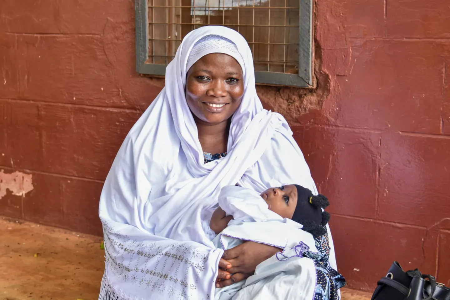 A mother smiles as she cradles her baby during a health visit at the Tamale West Hospital.