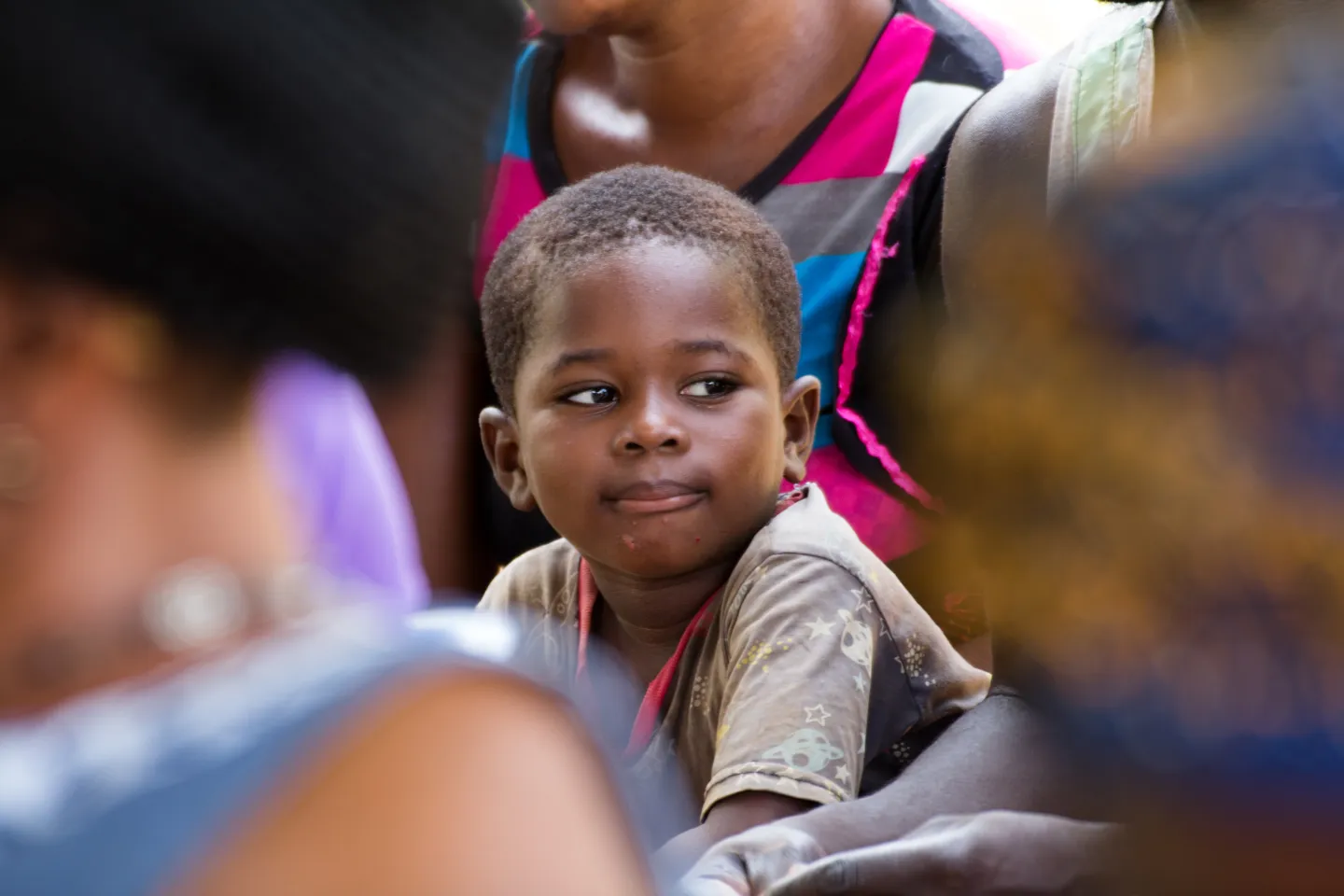 A boy sits with community members during a village meeting in Dambai.