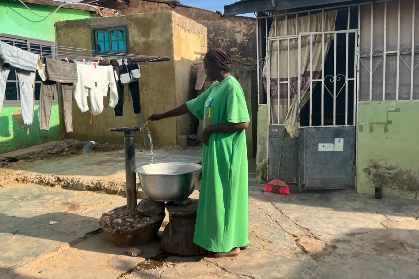 A lady fetches water at a tap in a compound house.