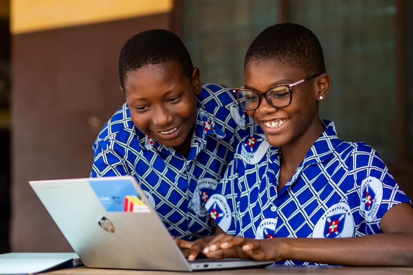 A school boy and girl happily learning on a laptop.