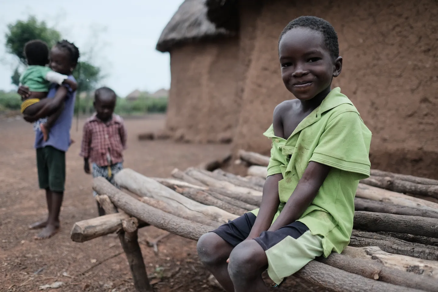 A young boy sits in front of his home in Gbandu in the Northern Region