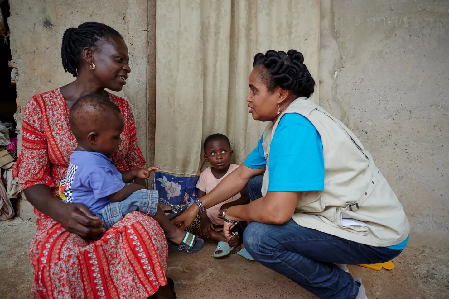 Ms. Charity Kikoi, UNICEF Social Behavior Specialist, speaks about children&rsquo;s vaccination and childhood diseases to Selina, who sits in front of house with her children in a village Hiampenika in Tweapease place in the region of Ashanti in Ghana. West Africa.