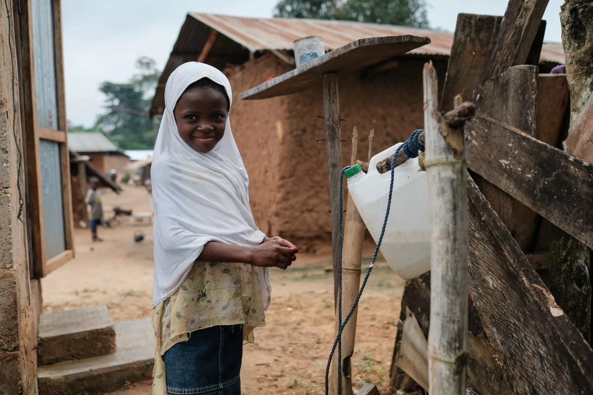 Altu Adamu in front of the "tippy tap" next to her family's latrine in the community of Ahmansu Junction in the Volta Region of Ghana.