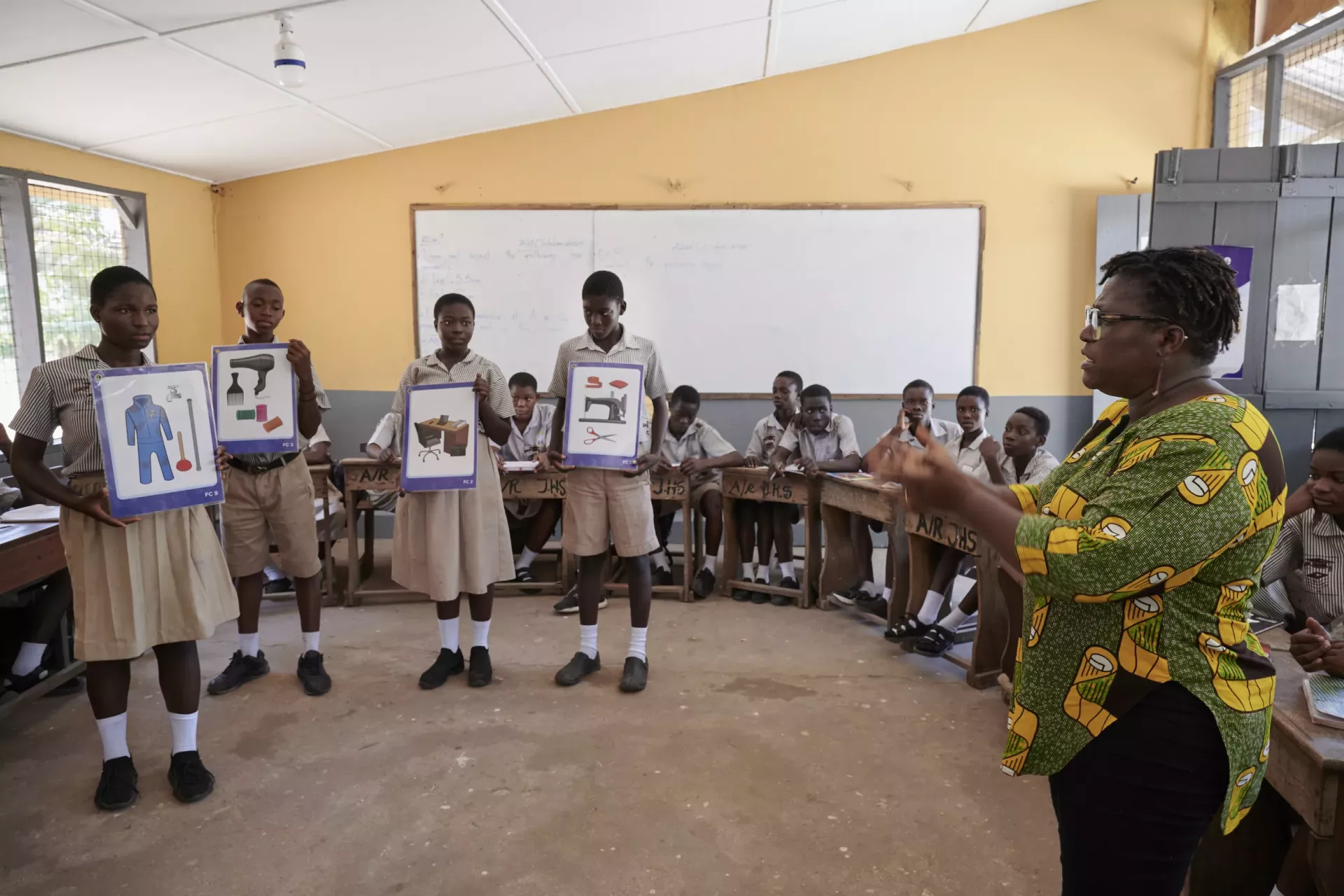 Vicentia, community development officer at the AMA, speaks with students holding flashcards. 