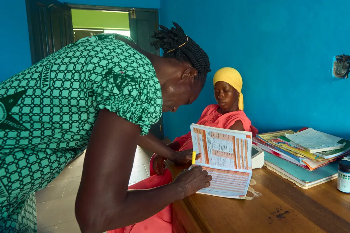 A midwife carefully records clinical details and updates a pregnant woman's health record during a routine antenatal visit. Part of the UNICEF and KOICA CHPS+ Project Phase II, accurate record-keeping ensures frontline health workers can effectively track vital signs and progress throughout each trimester.