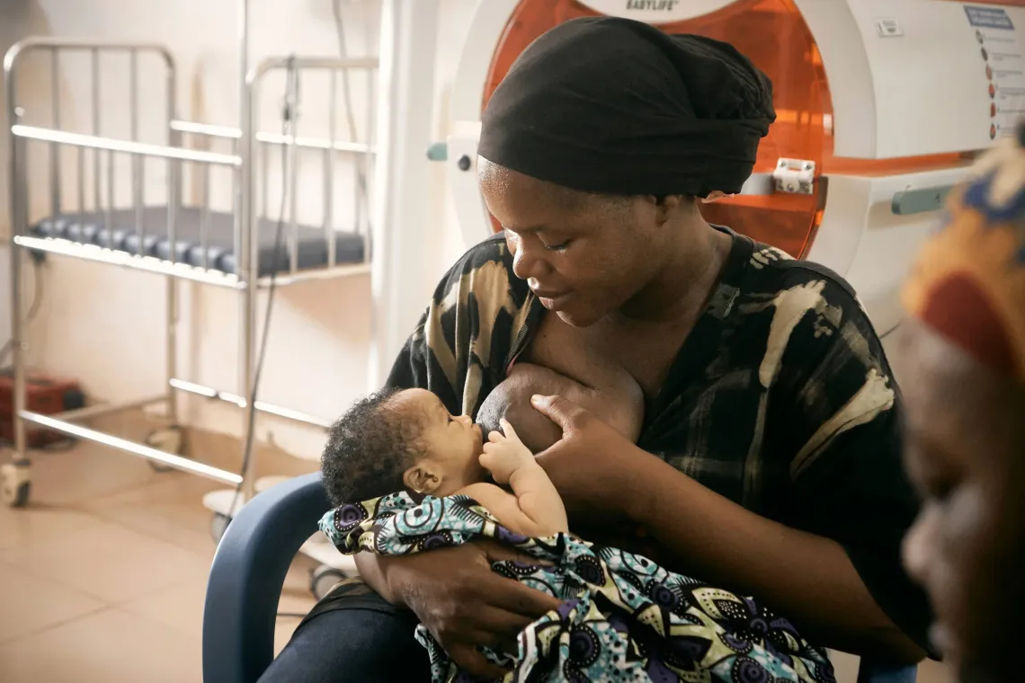 A mother cradles and breastfeeds her newborn during a postnatal care session after delivery.