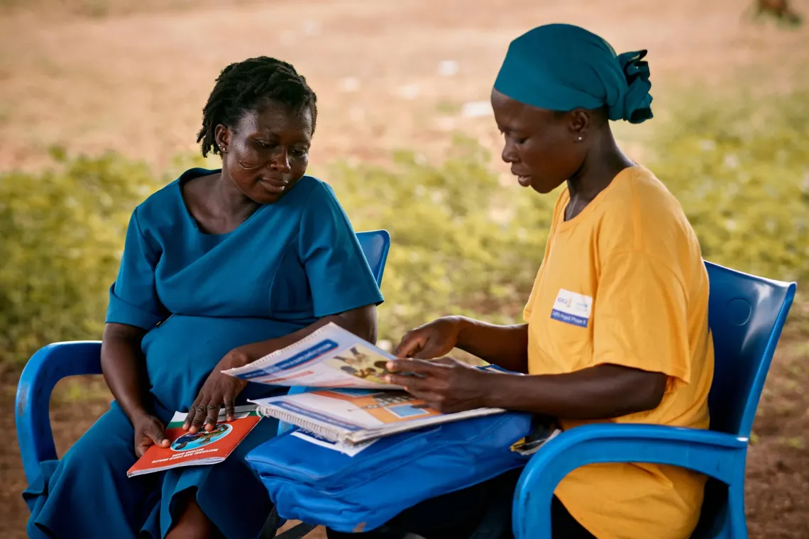 Community Health Volunteer Aida Bugre (34) uses illustrated guides to share maternal health and nutrition advice with Mary Sapak (31), who is 25 weeks pregnant, during a home visit in Gundoug/Mihiiboug, Upper East Region, Ghana.