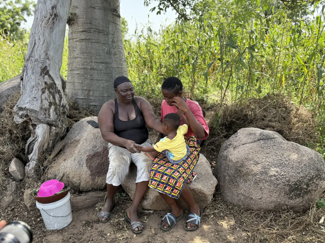 Beatrice sits with her mother and child. 