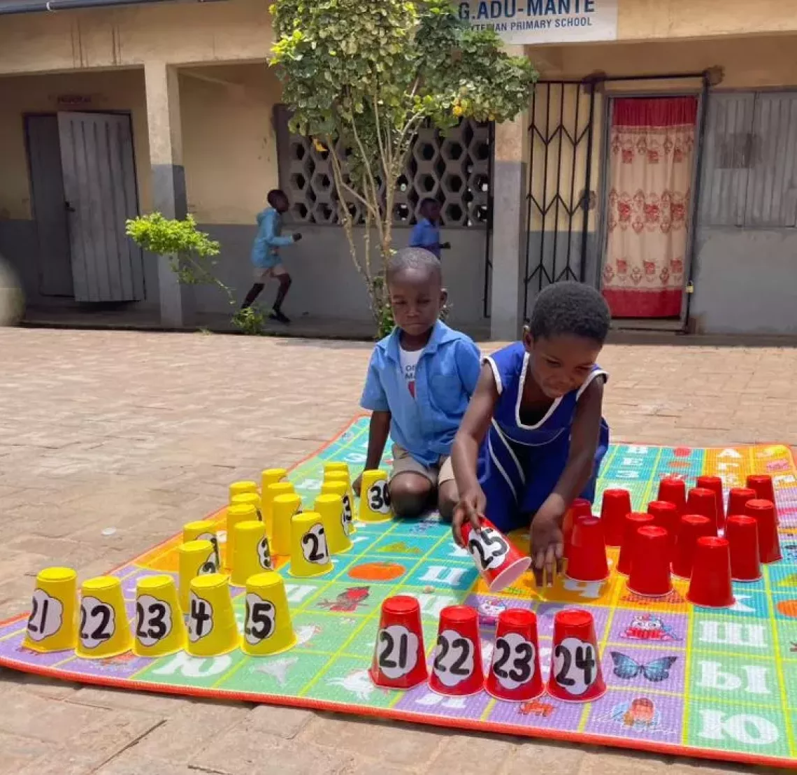 Two pupils counting using disposable cups as outdoor games.