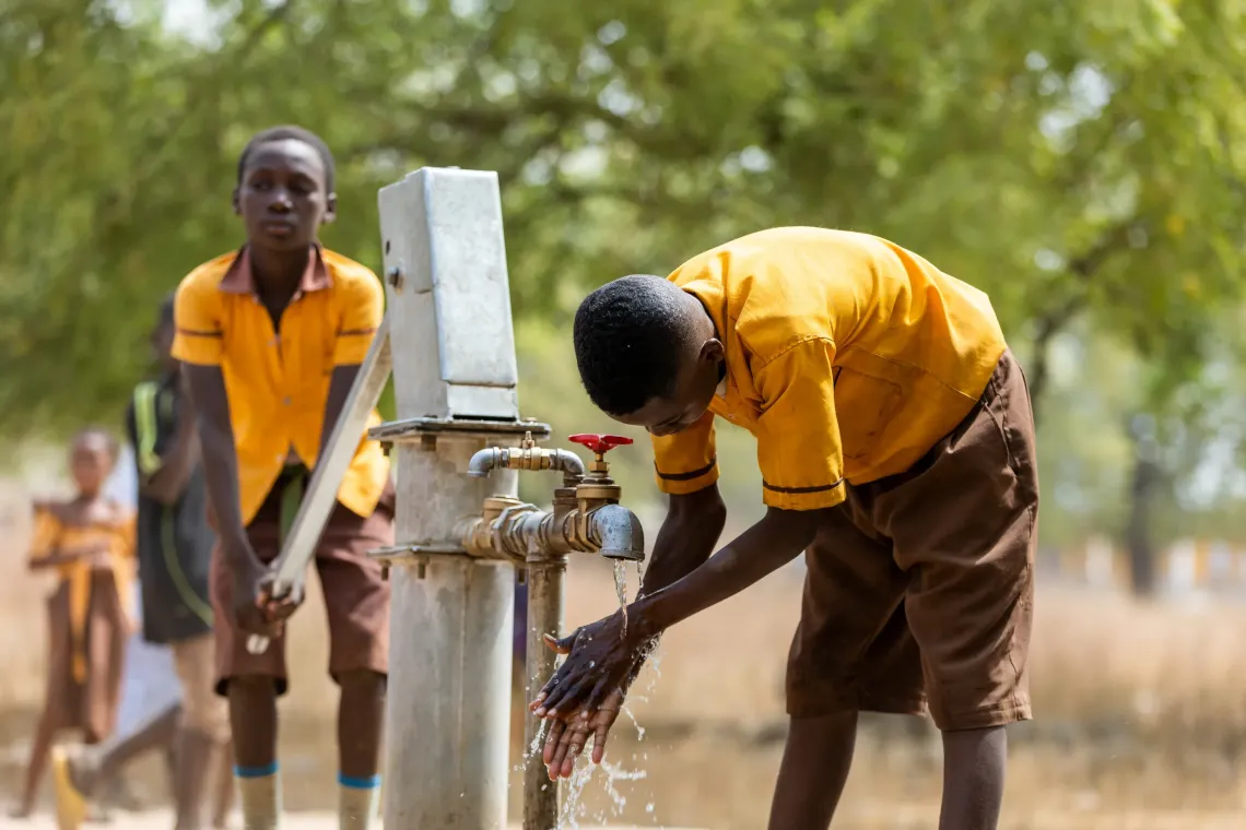 Boy washes hands with the help of a mechanised borehole at Sapelliga..