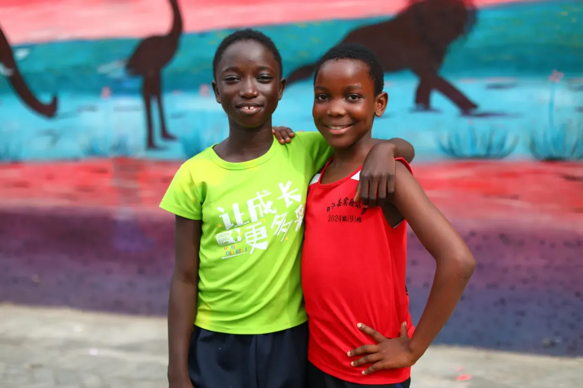 Two girls stand together with smiles.