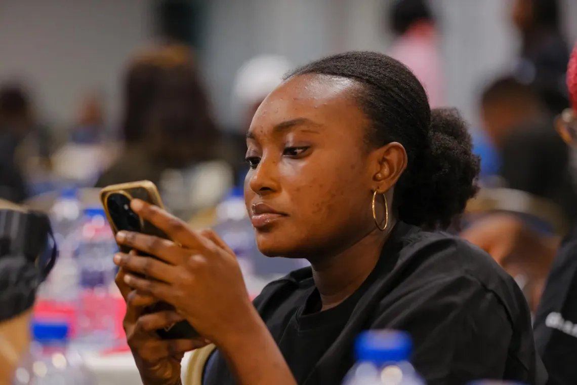 A U-Reporter focused on taking a poll on her smartphone at a U-Report event in Accra.