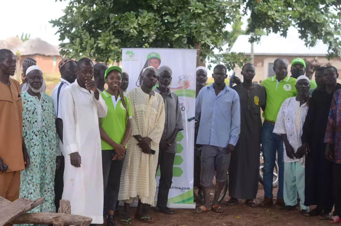 Agrivest Africa team together with the community men smile whilst standing.
