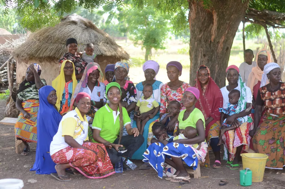 Jennifer together with the community women with smiles as they sit.