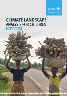 Two young girls carry firewood in large pans walking along the roadside.