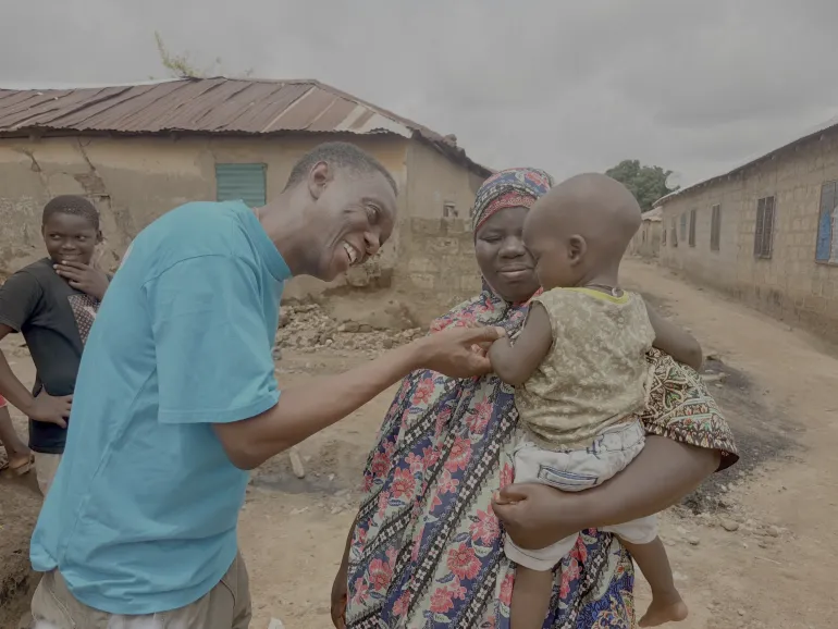 WASH Chief, Arnold Cole interacts with mother and child in a community.