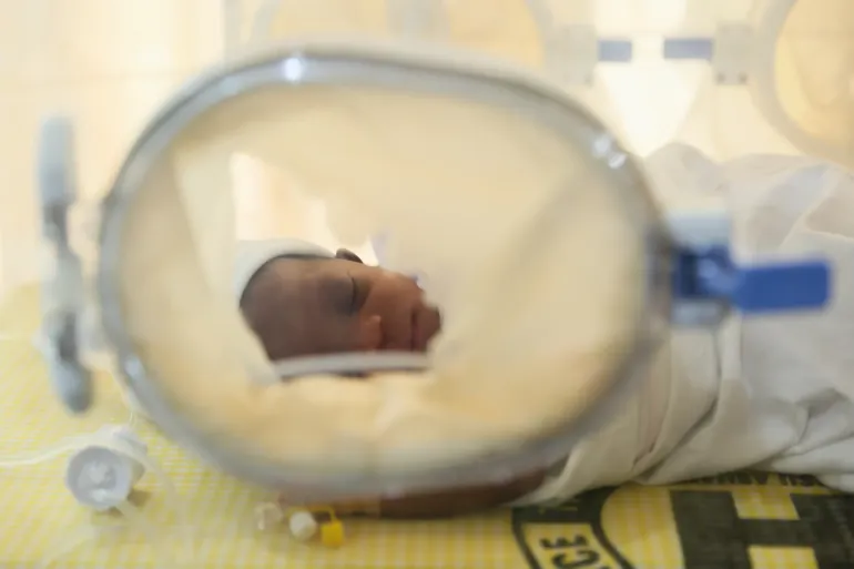 A newborn baby in an incubator in a health facility.