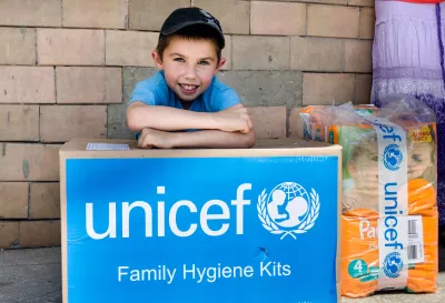 A boy leans on UNICEF family hygiene kit his mother has received during delivery of UNICEF humanitarian aid to families living in Toretsk, Donetsk regions, on 17 June 2016.