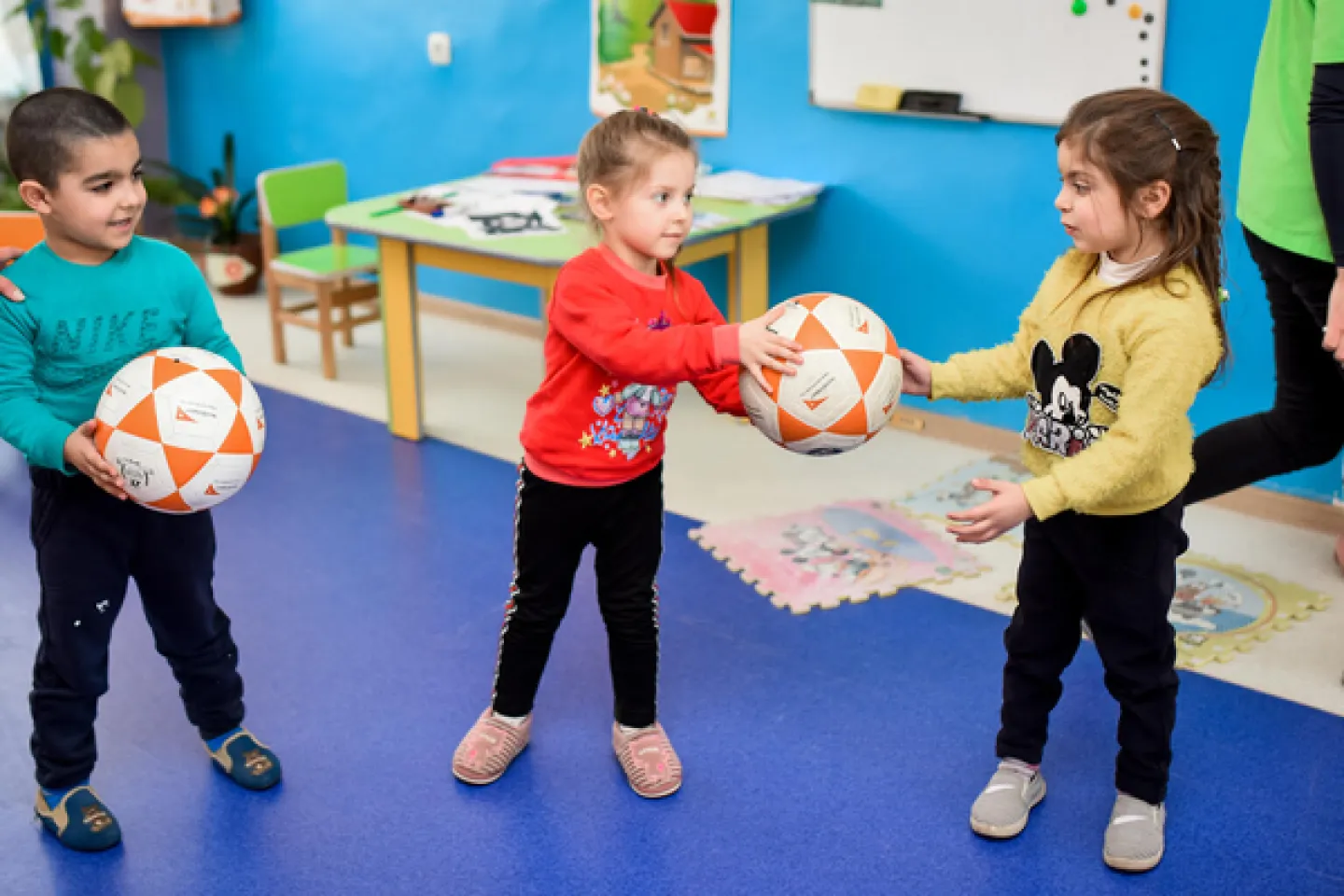 Two girls and a boy playing with a ball