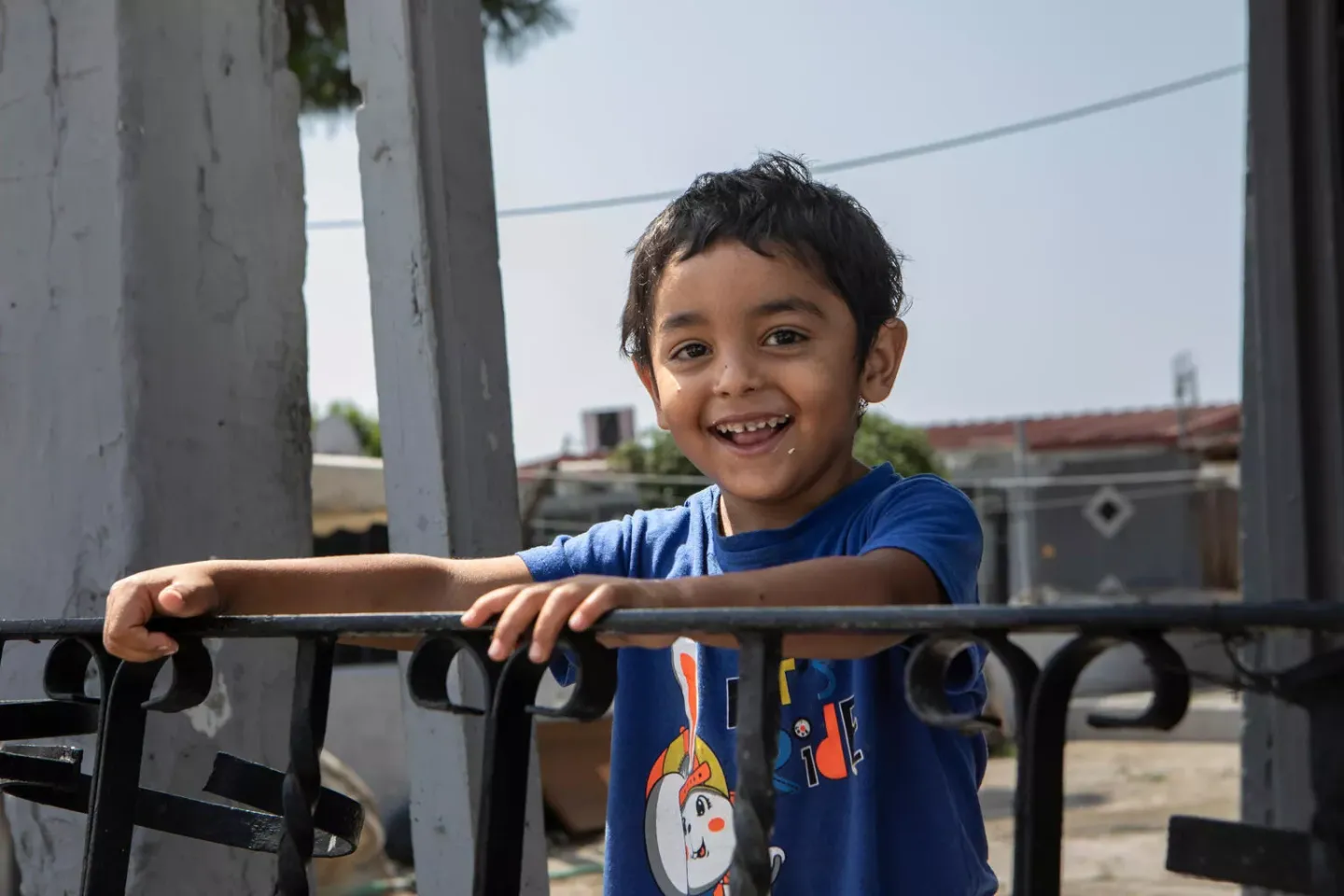 A young Roma boy smiles to the camera.