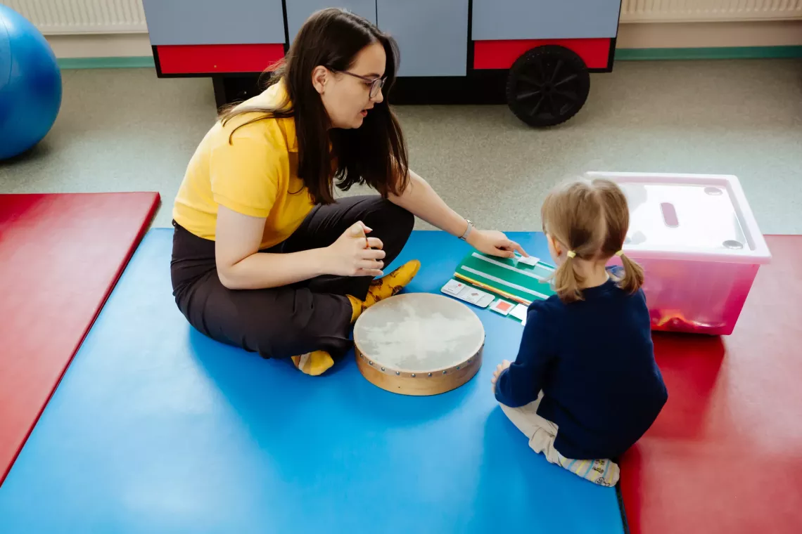 Theona, shown here at four years old, is shown receiving support from a speech therapist. Previously, she pulled on her mother's hand when she wanted to ask for something. After the sessions, she learned how to communicate her feelings and wishes.