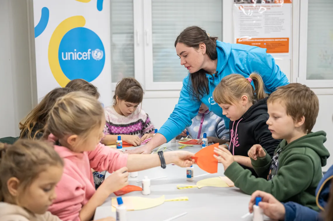 Social worker Krystyna Kolokolova shows children how to make a Christmas decoration.