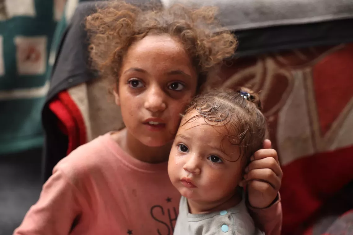 Rama, 11-year-old with her one-year-old sister Malak inside their tent at Deir al-Balah, the Gaza Strip.