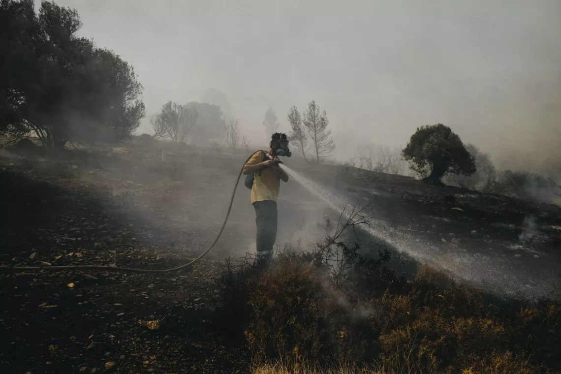 A volunteer firefighter helps put out a fire in the Plaka area,in Keratea, 40km southeast of Athens, Greece (2021).