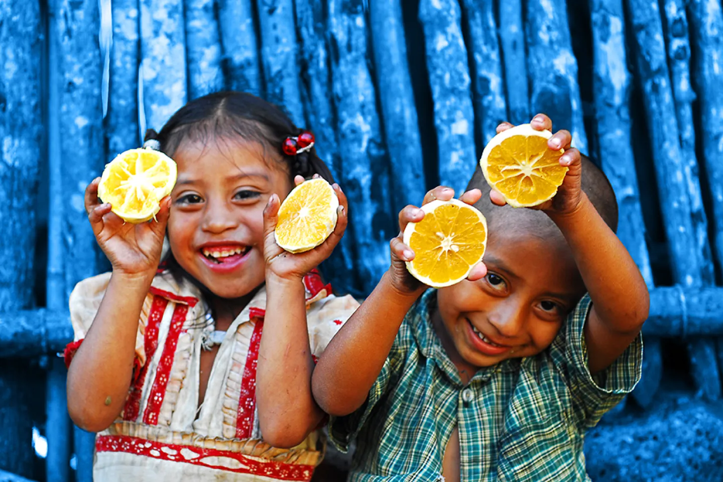 ni&ntilde;a y ni&ntilde;o indigena comiendo naranjas