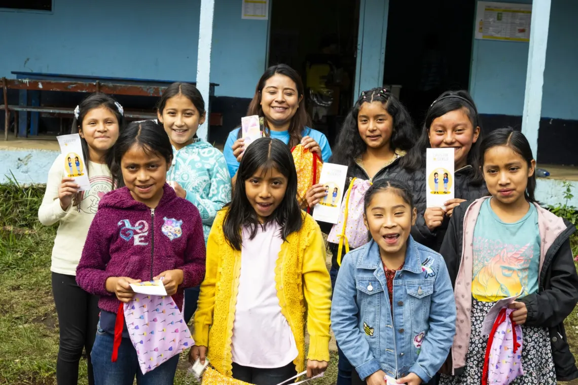 Ni&ntilde;as frente a su escuelita junto a personal de UNICEF con sus bolsos nuevos con instrumentos de higiene menstrual