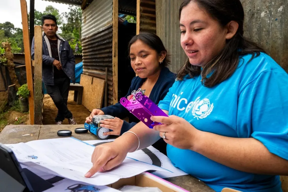 Personal de UNICEF le muestra a adolescente como usar robot