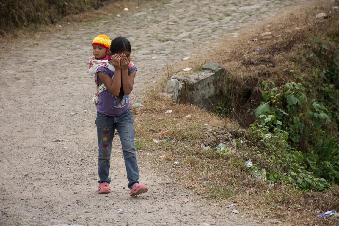 ni&ntilde;a cargando a un beb&eacute; en su espalda
