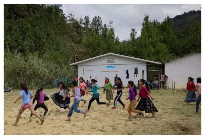 Ni&ntilde;as y ni&ntilde;os jugando con una pelota de futbol enfrente de una escuela apoyada por UNICEF.