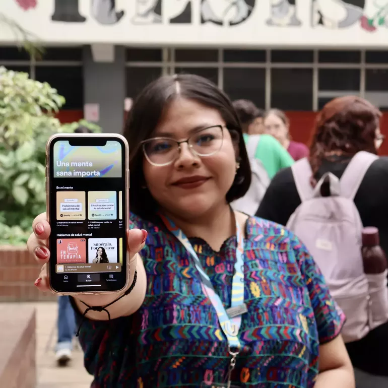 Joven sostiene su movil y muestra el poadcast una mente sana importa.