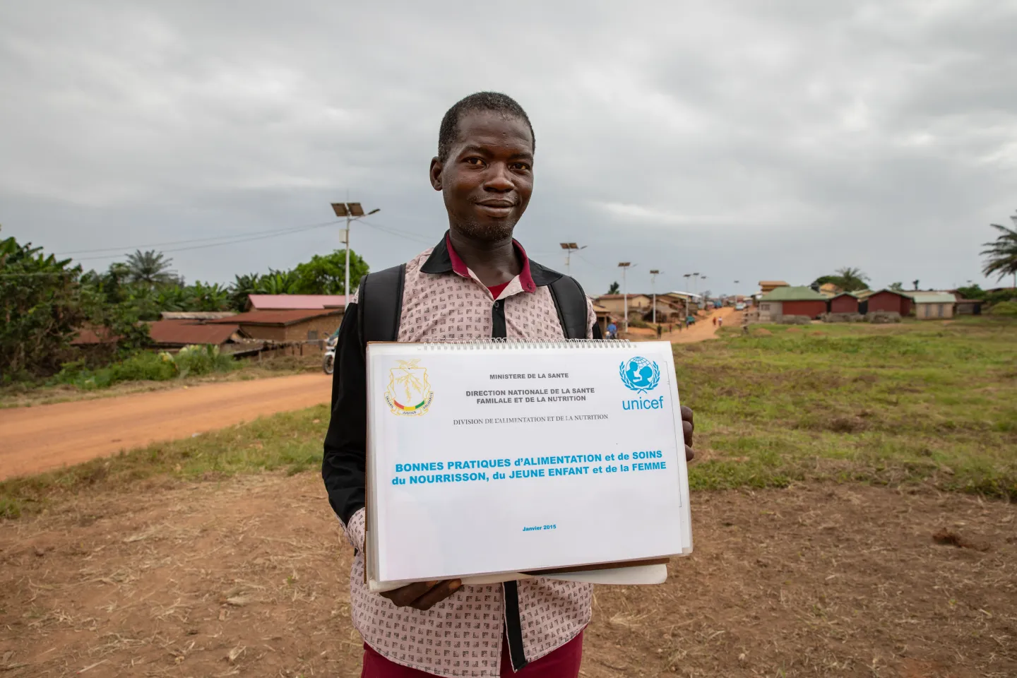 Mr. Felice Yoamou, Community Relay carries a visual box about good feeding and care practices for infants, young children and women, Kobéla convergence community, Nzérékoré region, Guinea. 