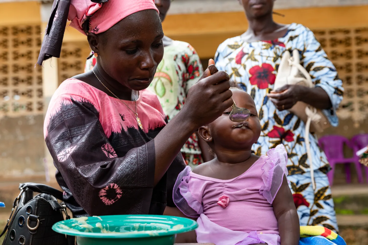 One-year-old Therese Bonimy eats porridge during a cooking demonstration to educate mothers about proper nutrition for their young children, Bossou commune, Nzérékoré region, Guinea.