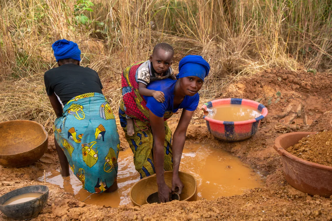 Accompagn&eacute;es par leurs enfants, des femmes recherchent de l'or dans la zone mini&egrave;re de Doko, Siguiri, Guin&eacute;e.