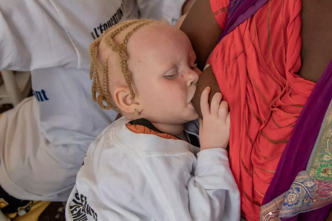 A mother breastfeeds her baby girl during the celebration of the Day of the African Child in Conakry, Guinea.