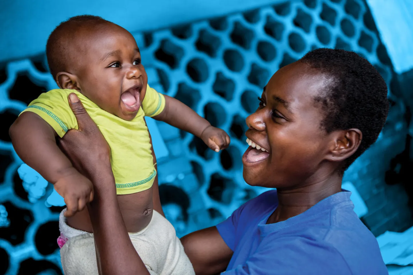 A mother holds her child up as she queues with others to register her child's birth