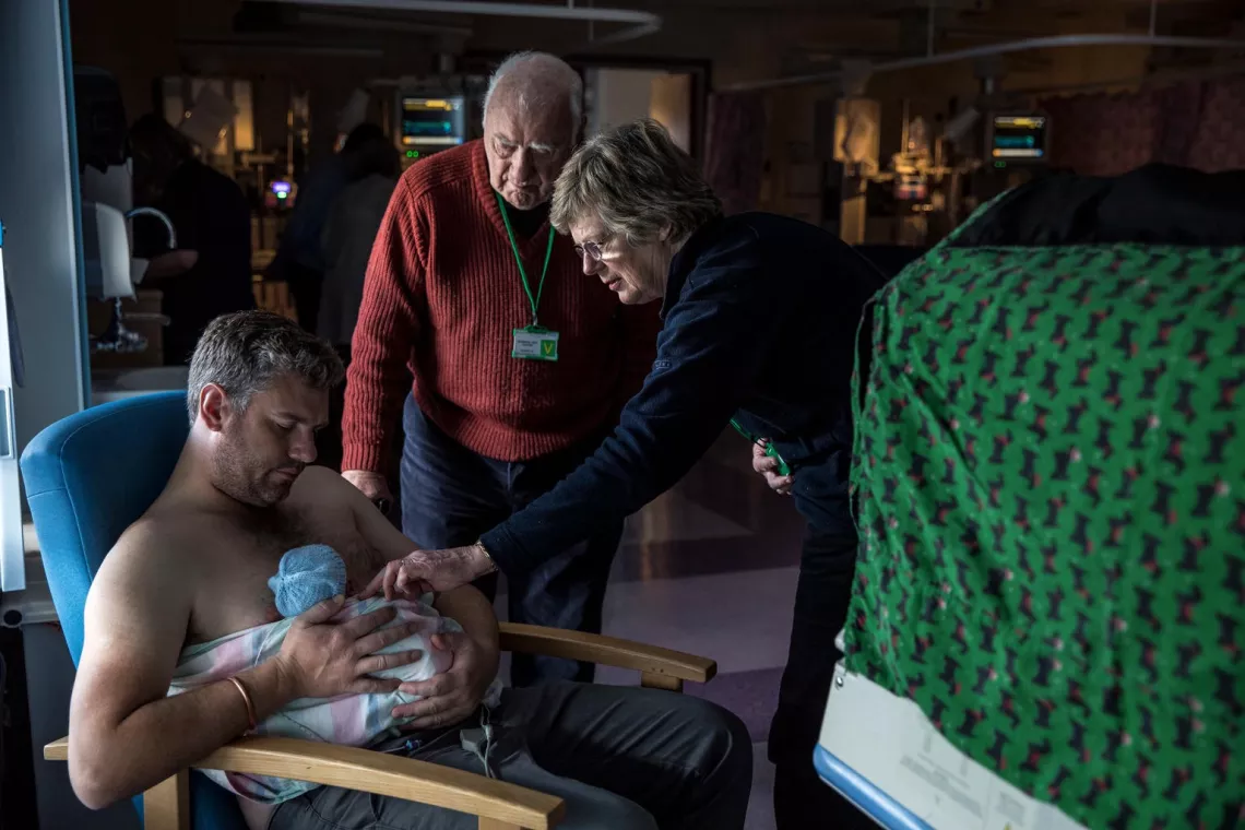 Dad holds his newborn baby against his bare chest