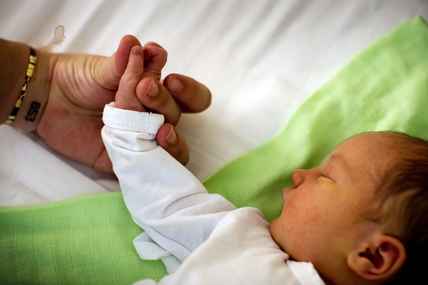 Baby sleeps holding parent's hand