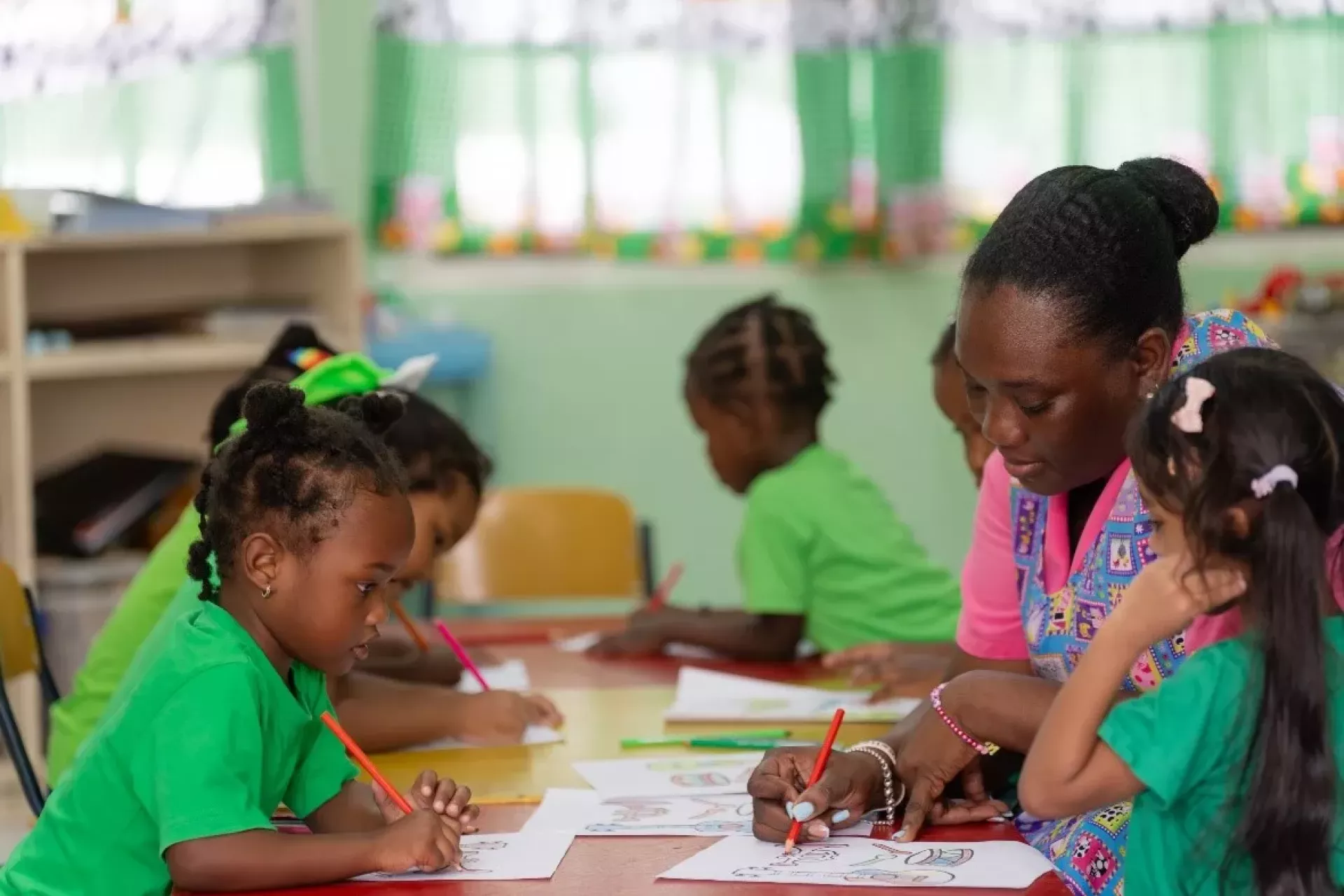 Teacher Samantha shares a joyful moment with her  students as they color together during a morning activity.