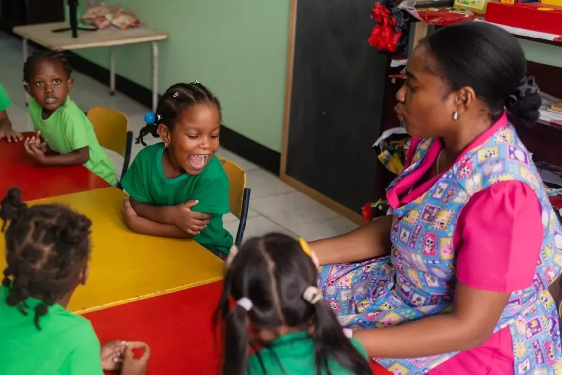 Teacher Xiomara shares a lighthearted moment with one of her  students, who burst into laughter during their playful conversation.