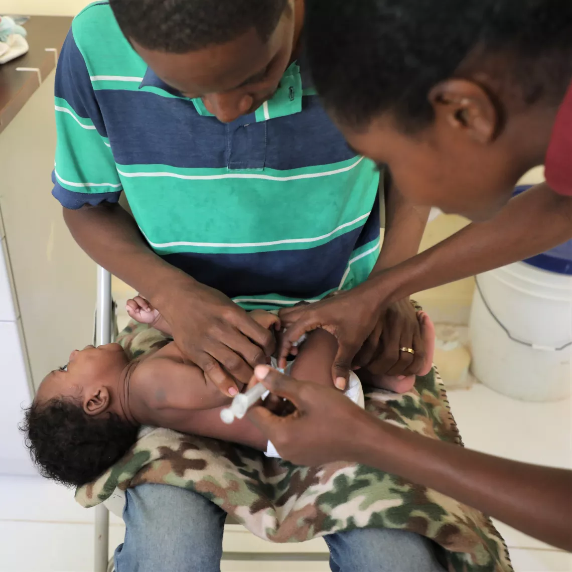 Jean brings his child to receive his vaccine