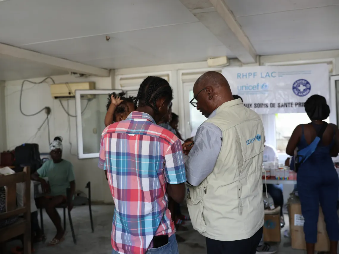 Un membre du personnel de l&rsquo;UNICEF sensibilise un p&egrave;re accompagn&eacute; de son enfant. 