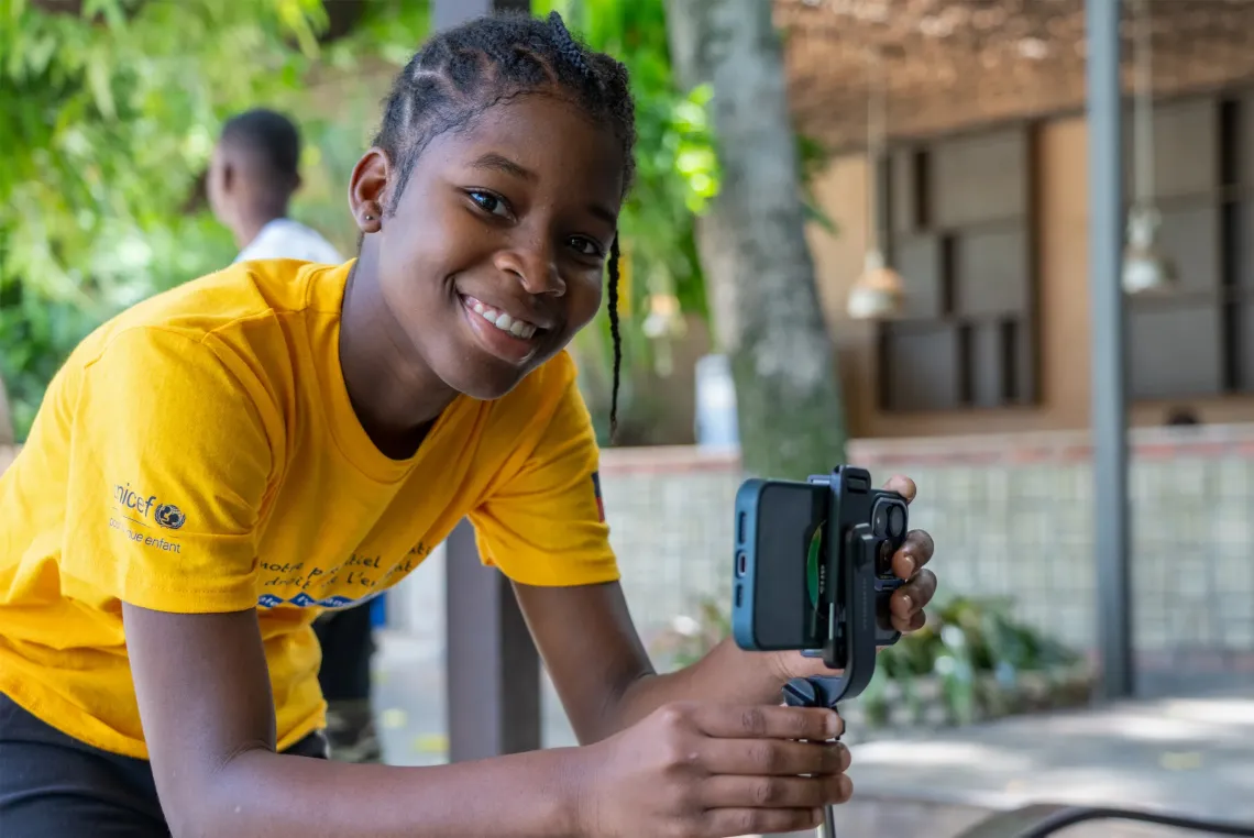 A young girl films with a phone