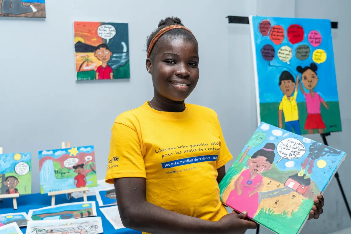 A young girl smiling and showing a painting