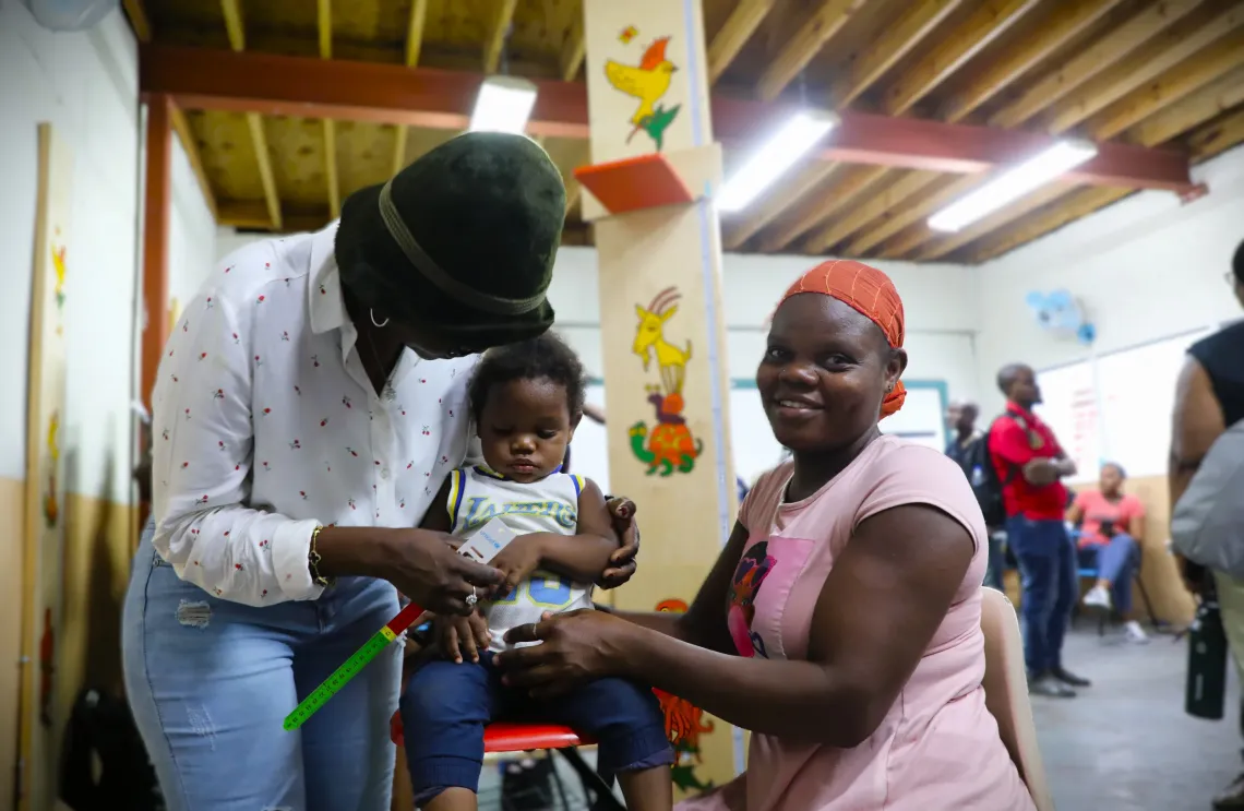 A health agent using a MUAC tape to measure the mid-upper arm circumference of a child
