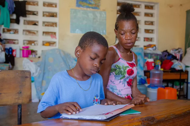 *John, 9, is sitting next to his mother while studying.